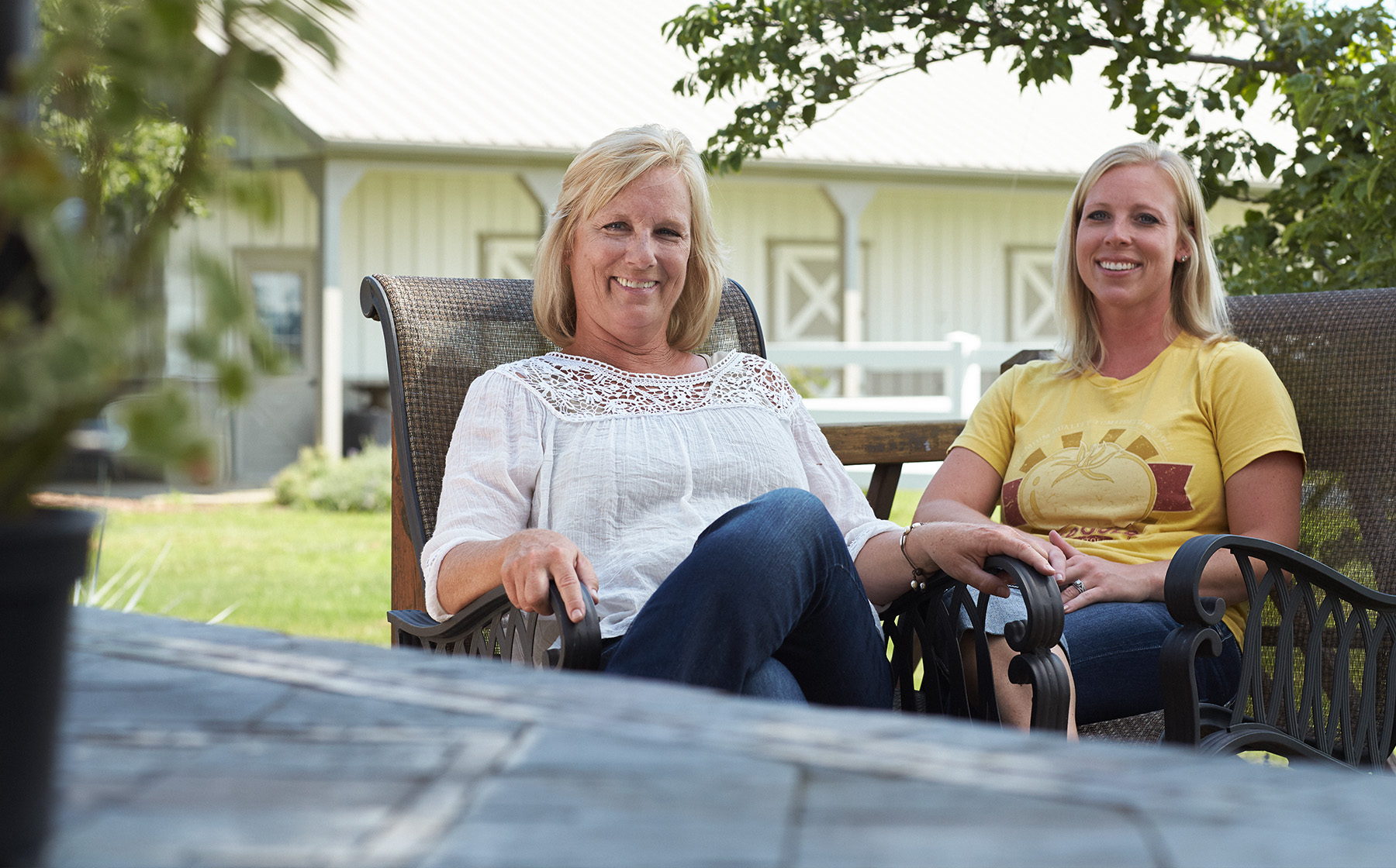 Image of Keesling Farms Growers for Red Gold Tomatoes Kim and daughter Kaycie in chairs outside with barn in background