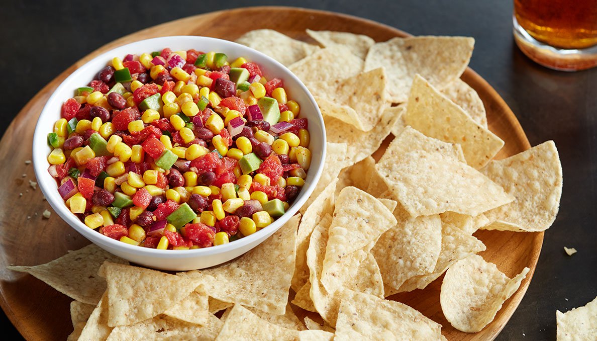 Image of Corn Salsa on wood tray with tortilla chips