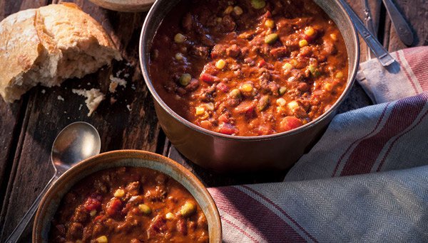 Image of Dads Chili in metal pot with bread and one bowl full of chili