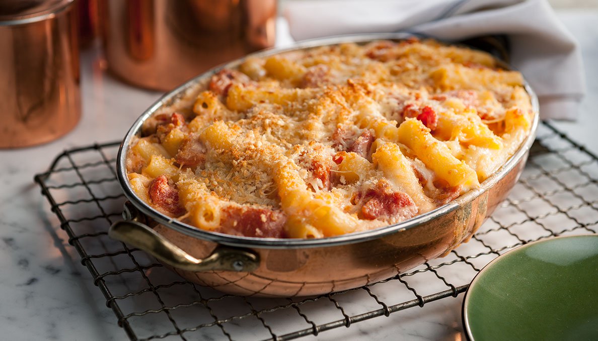 Image of Fontina Macaroni and Cheese with diced tomatoes and crunchy topping in a copper oven dish