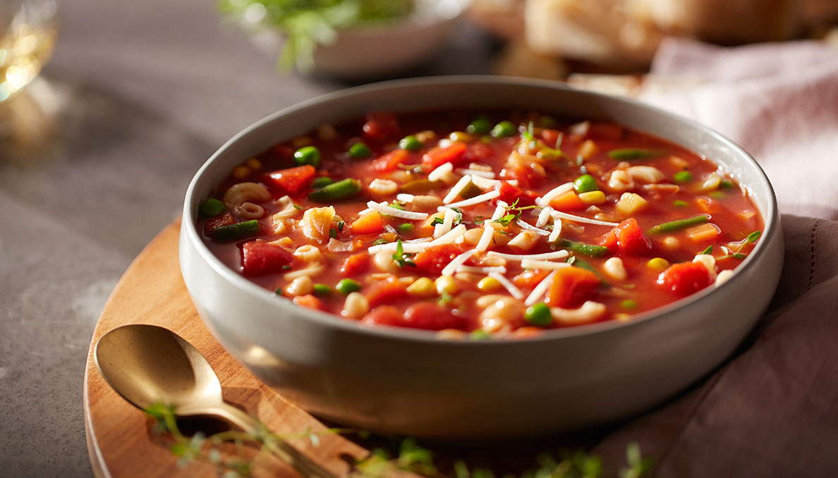 image of minestrone soup in a white bowls with a spoon using canned diced tomatoes