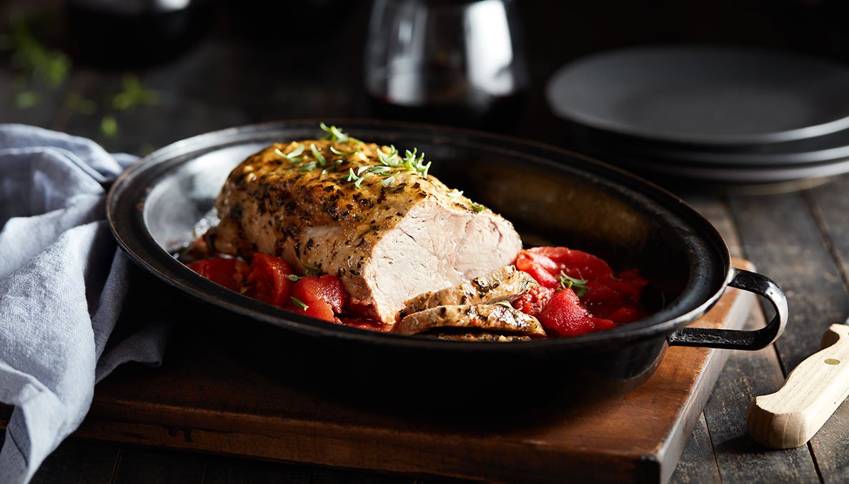 Image of pork loin with canned tomatoes in a black slow cooker insert