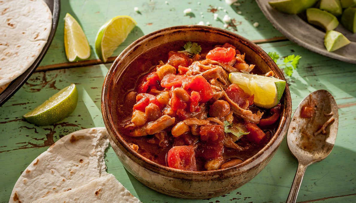 Image of Pork Pozole with lime wedges and tortillas