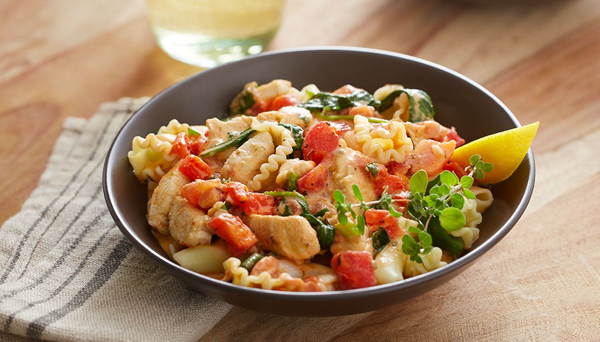 Image of Red Gold recipe Creamy Chicken Florentine Pasta in black bowl and diced tomatoes