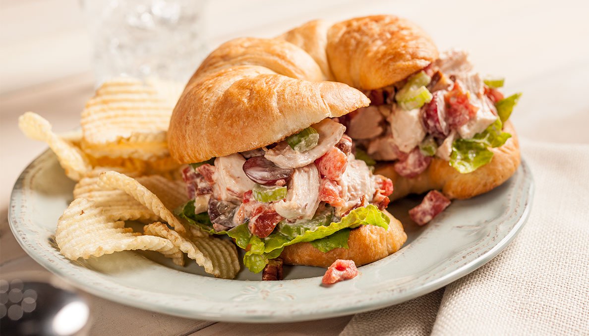 Image of Sassy Chicken Salad sandwich chicken salad with grapes celery diced canned tomatoes and chicken on a croissant 