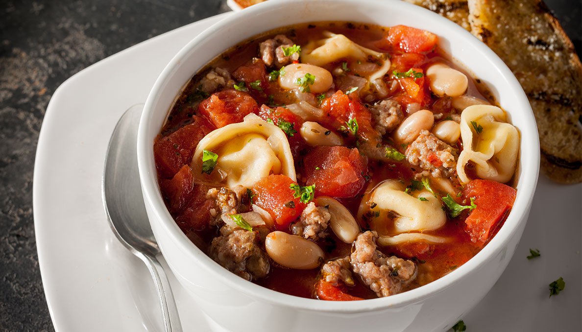Image of a bowl of Sausage Tortellini Soup in white bowl